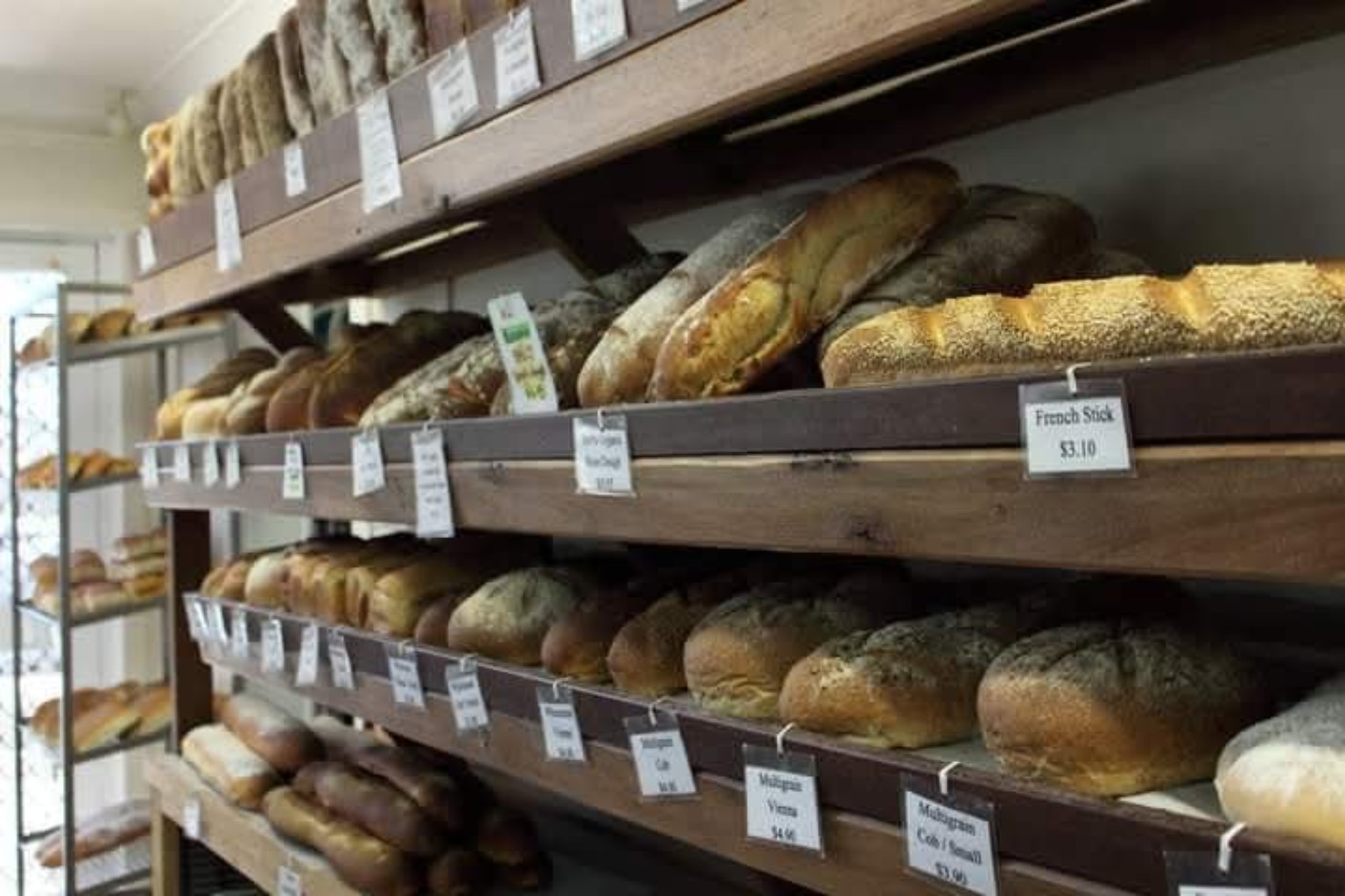 A selection of crusty and seeded loaves on wooden bakery shelves